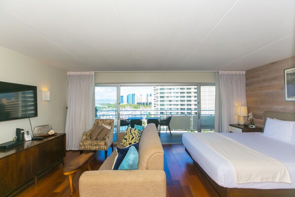 A hotel room with a large bed, a sofa, a desk, and a balcony with a city view. - Free WiFi/No Resort Fees/Oceanview at the Ilikai Hotel!  Beautiful Sunset Views! (Honolulu)