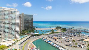 A marina with boats, a parking lot, and a beach with palm trees.
