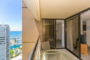 A balcony with a glass door leading to a room, a chair, and a table.