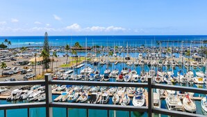 Un puerto deportivo con numerosas embarcaciones amarradas, un cielo azul despejado y vistas al océano.