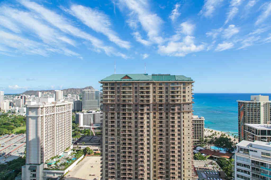 A high-rise hotel with a view of the ocean and cityscape.