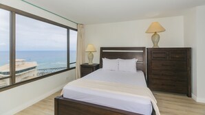 Ein Hotelzimmer mit großem Fenster, einem Bett, zwei Nachttischen und einem Beistelltisch.
