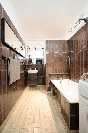 A modern bathroom with a large mirror, a sink, a shower, and a toilet.