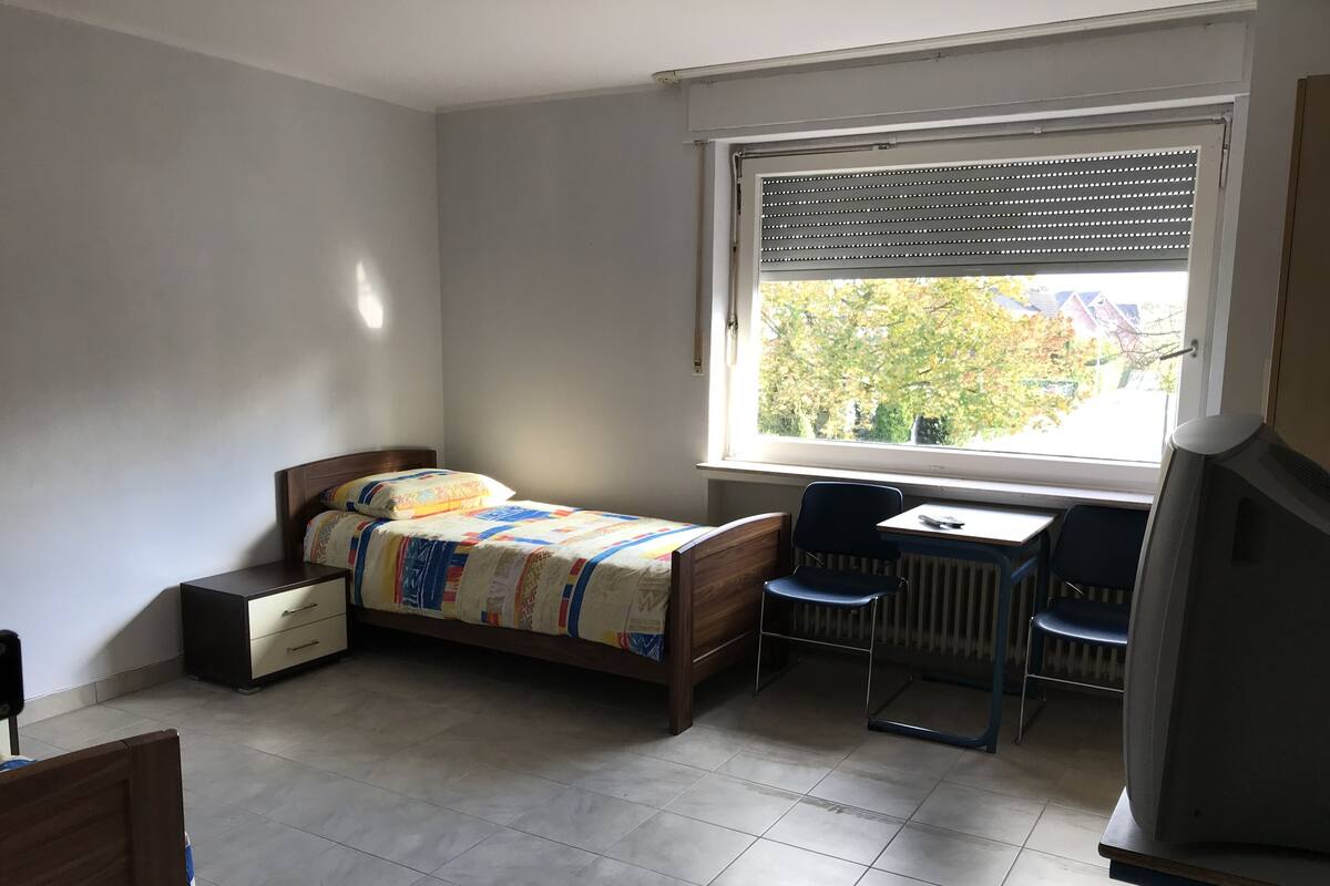 A bedroom with a bed, a desk, and a chair.