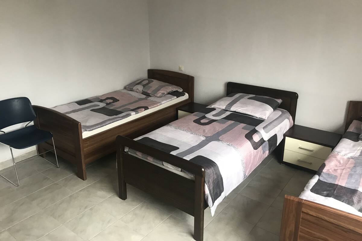 A room with two wooden beds, a chair, and a small table.