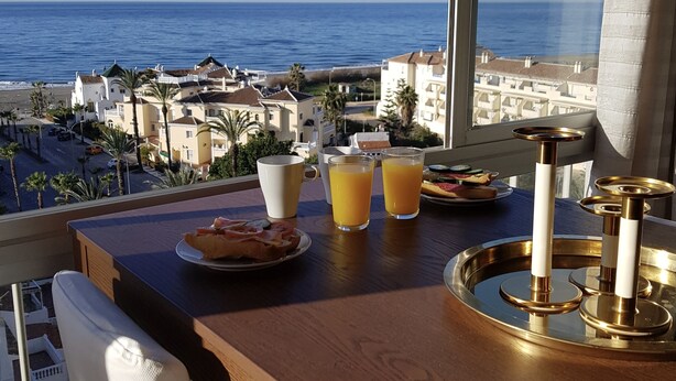 Et morgenbord med appelsinjuice, en tallerken mad og et fad med et lys.
