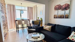 En moderne stue med sofa, sofabord og spiseplads.