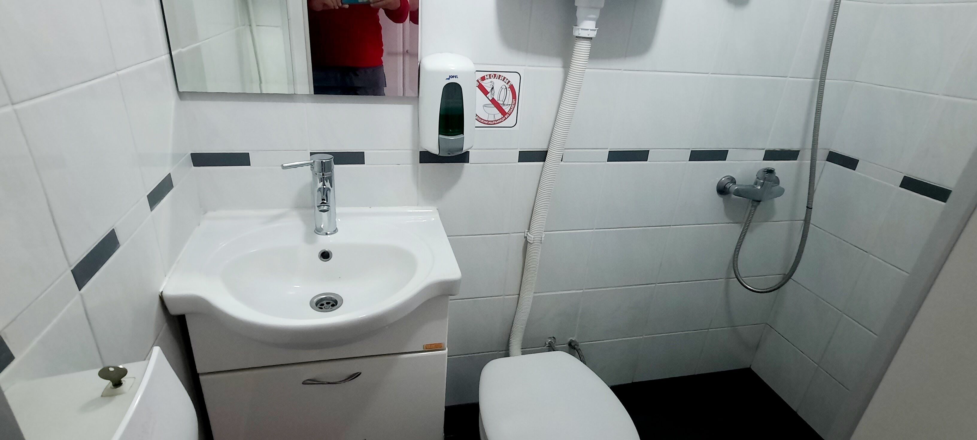 Um banheiro pequeno com pia branca, vaso sanitário e chuveiro.