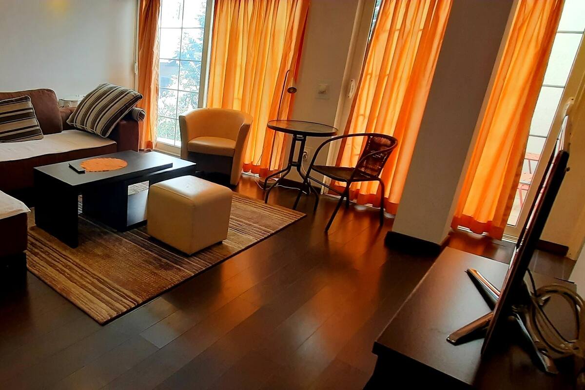 Ein modernes Wohnzimmer mit einem braunen Sofa, gestreiften Kissen, einem kleinen runden Tisch und einem Sessel.