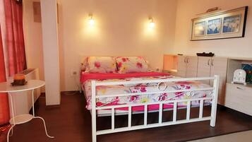 Un dormitorio con cama, una mesita, un armario y una lámpara fijada a la pared.