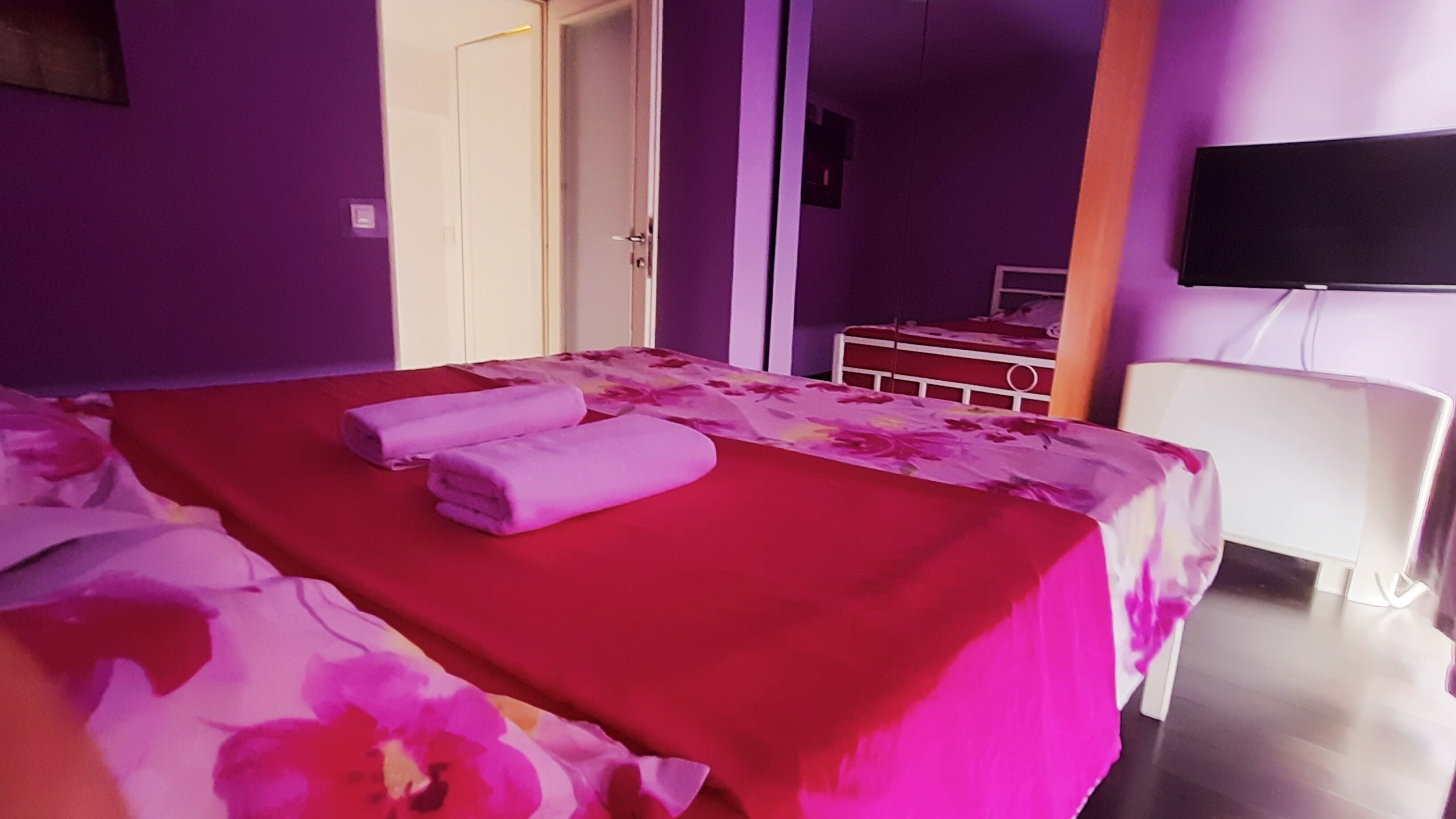 A hotel room with a bed, a television, and a desk.