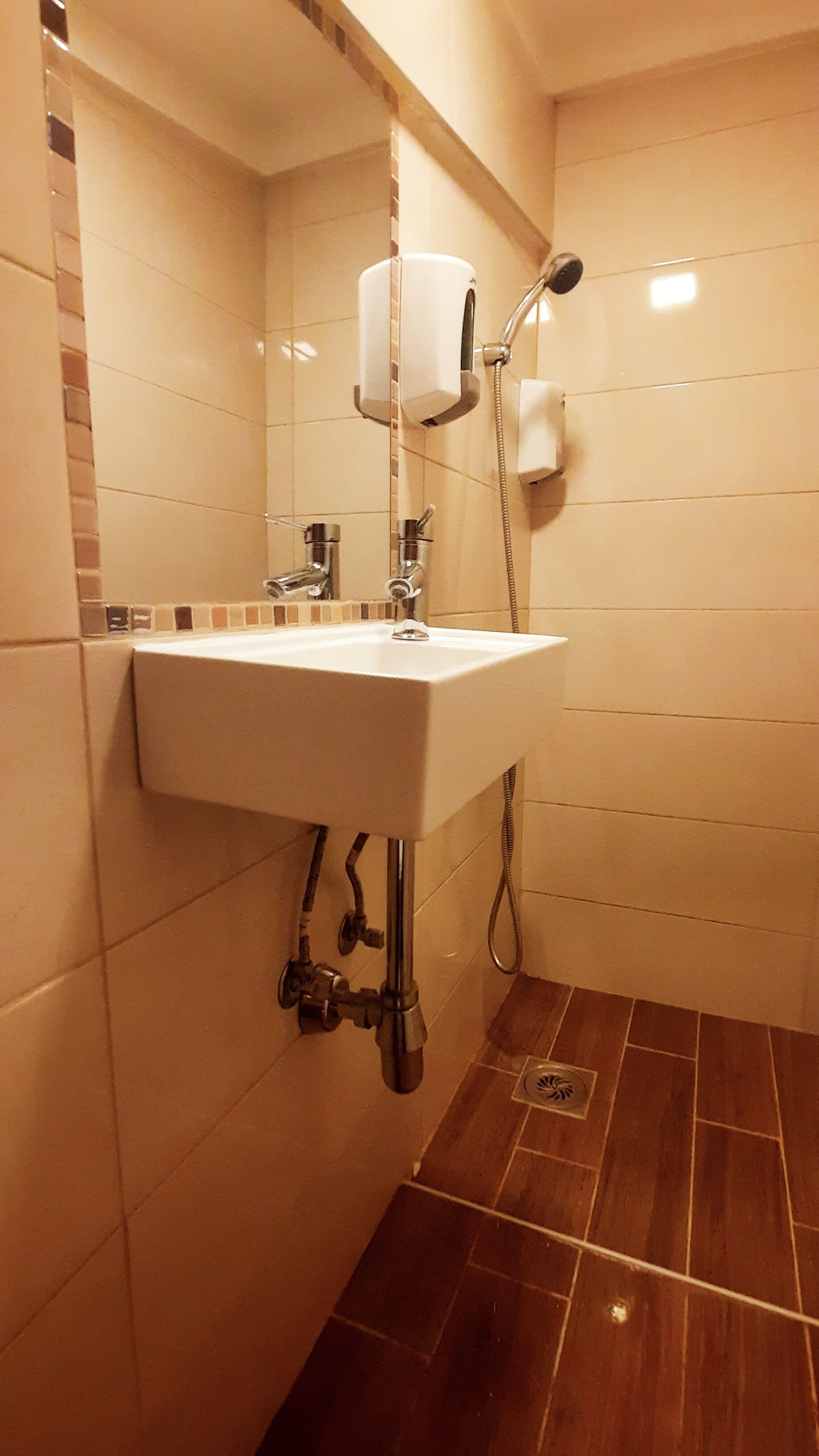 Een badkamer met een wit wastafel, een spiegel, een handdoekrek en een douche.