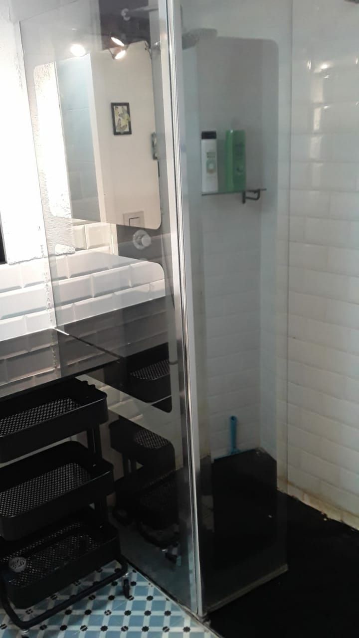 Une salle de bain avec une douche à parois de verre, un lavabo et une étagère contenant des articles de toilette.