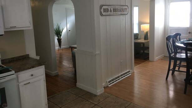 A kitchen with white cabinetry, a dining area with a table and chairs, and a sign reading "Bed & Breakfast."