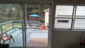 A room with a sliding glass door leading to a deck with outdoor furniture and a blue umbrella.