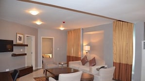 A modern living room with a sofa set, a coffee table, and a flat-screen TV mounted on the wall. - De Brass Suites Hotel (Yenagoa)