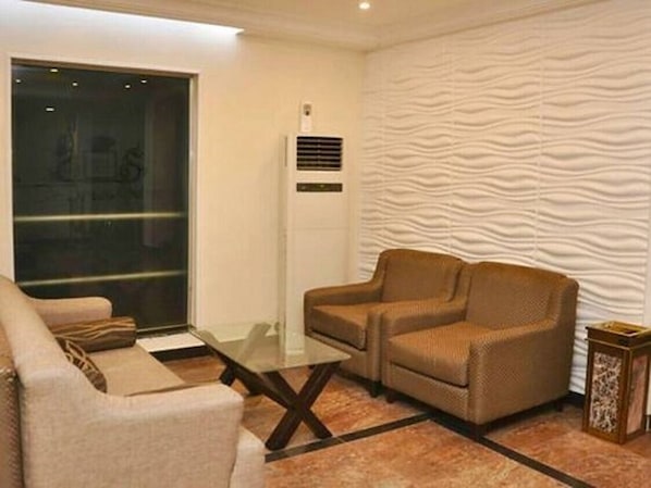A modern living room with a sofa, armchair, and glass coffee table.