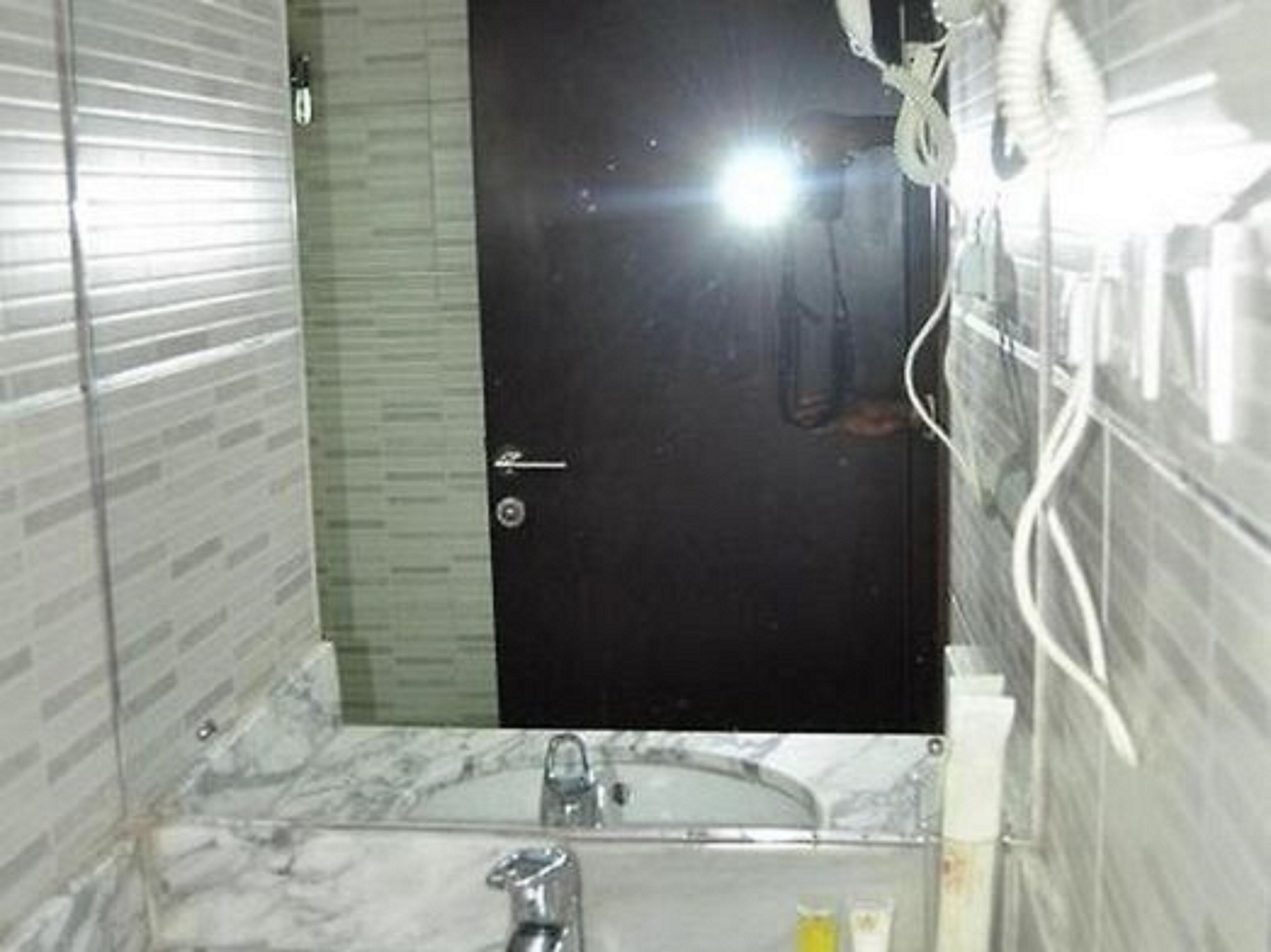 A bathroom with a marble sink, a dark door, and a shower area.