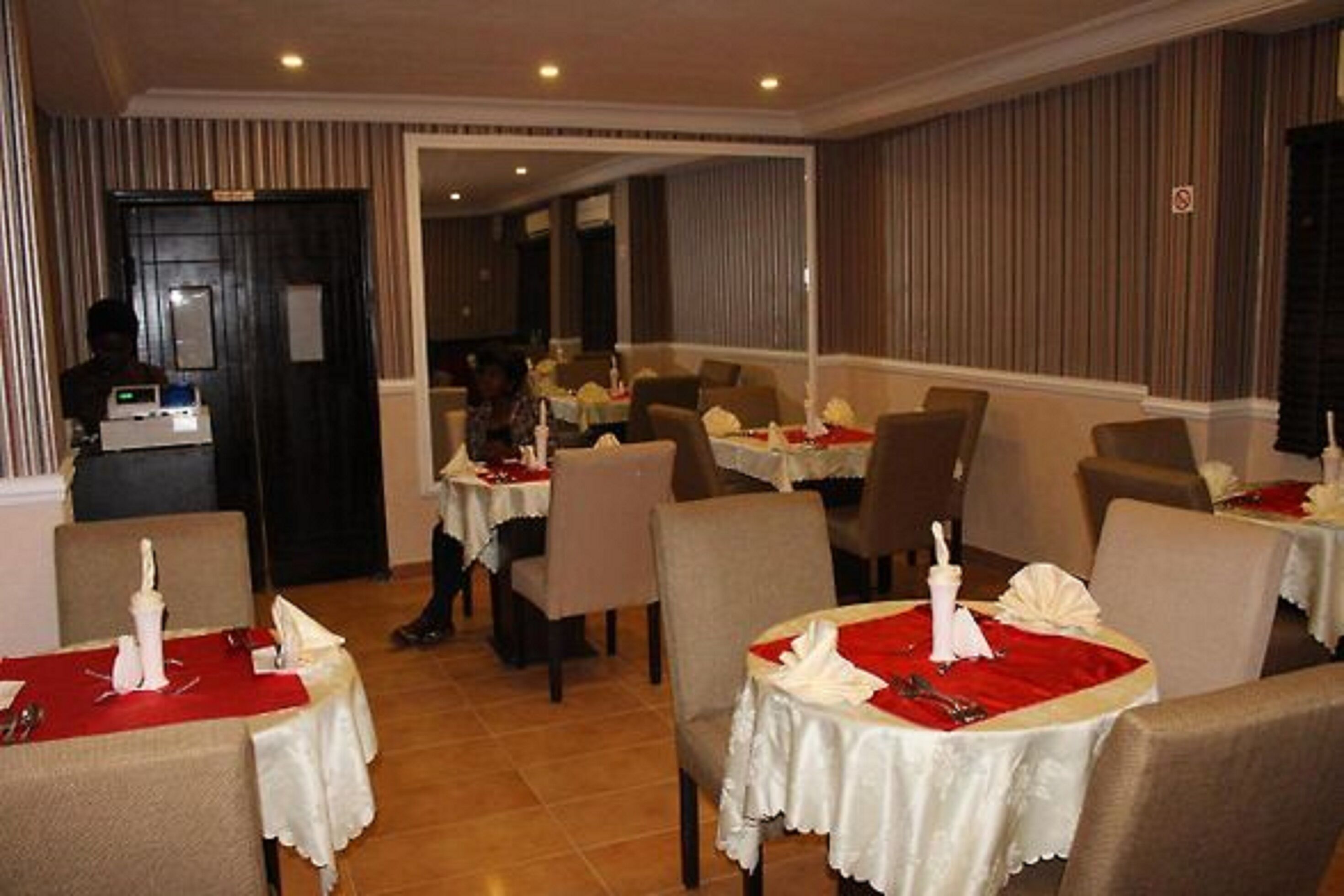 A restaurant with tables set for dining, featuring white tablecloths and red napkins.