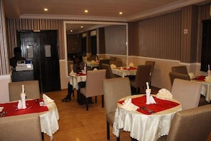 A restaurant with tables set for dining, featuring white tablecloths and red napkins.