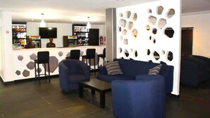 A modern lounge area with a bar, seating, and a decorative wall. - De Brass Suites Hotel (Yenagoa)