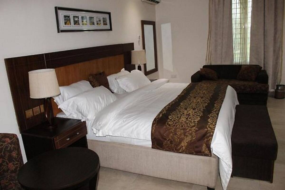 A hotel room with a large bed, a sofa, a small table, and a chair.
