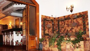 Een receptiezone met een houten receptiebalie, een decoratieve wand met een ruitpatroon en een kroonluchter.