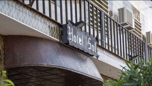 L’entrée d’un hôtel, avec une enseigne indiquant « Hôtel Sol », un porche et des plantes en pot.