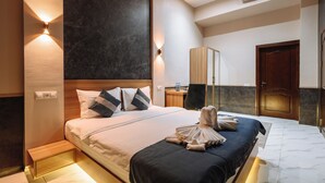 Une chambre d’hôtel moderne avec un grand lit, une tête de lit en bois, une table de chevet, un miroir et une armoire.