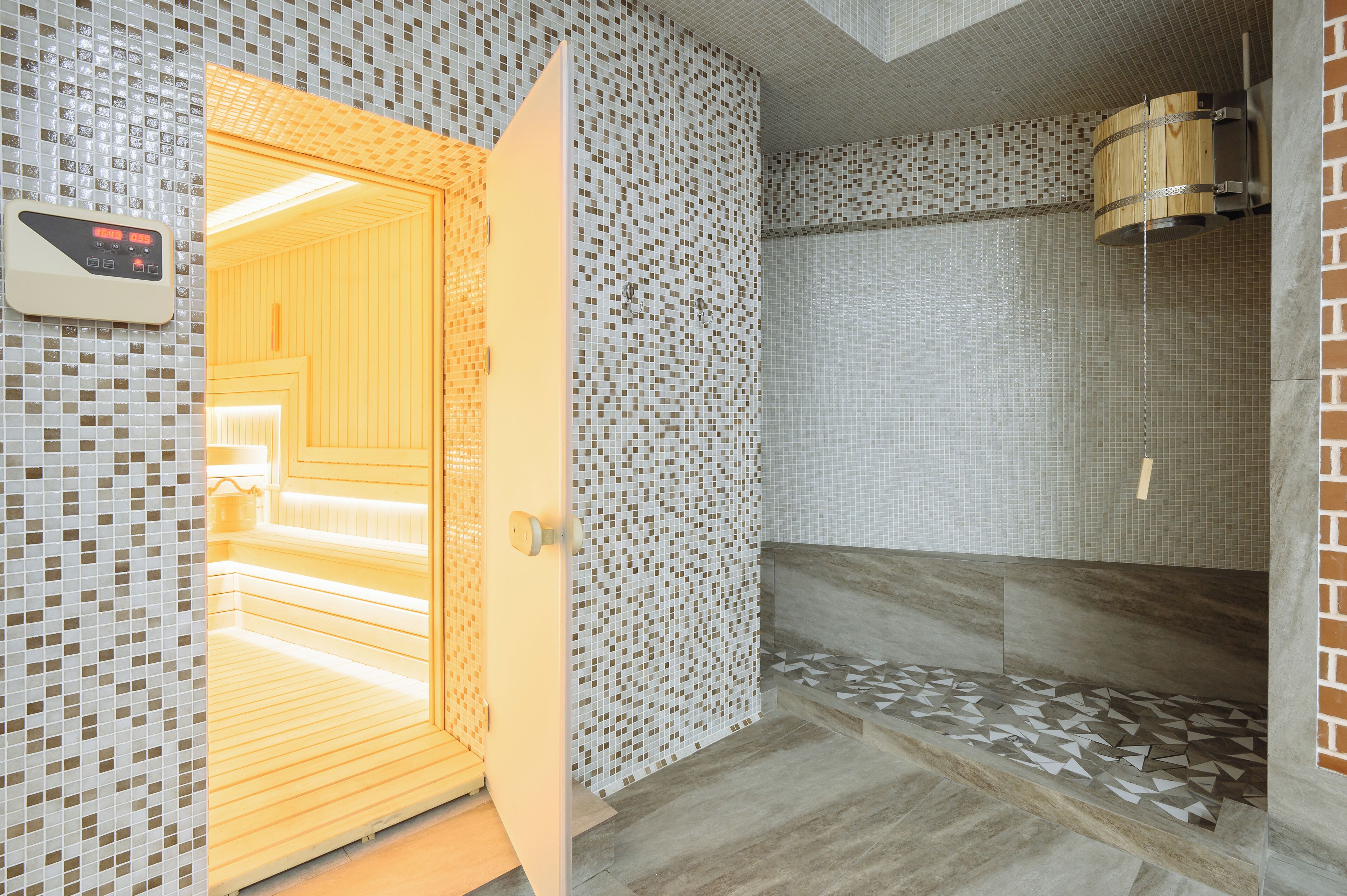 A bathroom with a shower, tiled walls, and a wooden door.