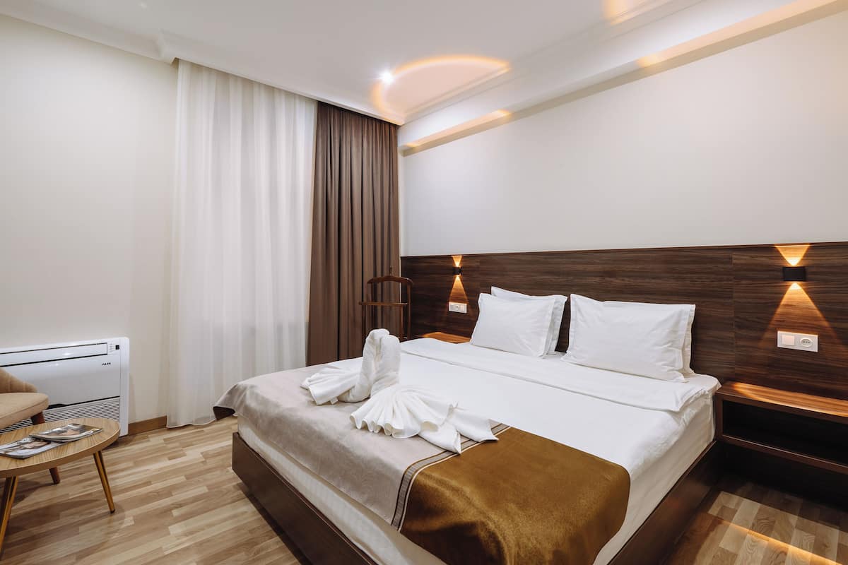 Une chambre d’hôtel comprenant un lit, une table de chevet, une chaise, une table et un radiateur fixé au mur.