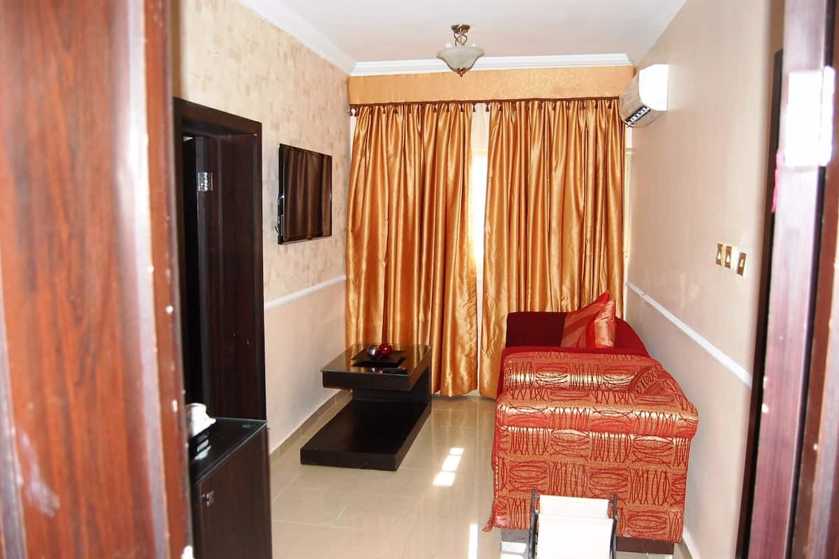 A compact hotel room with a bed, a small table, a TV, and a window with curtains.