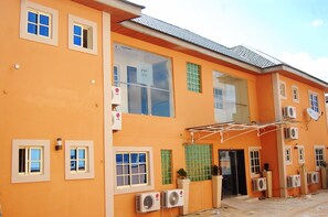 A multi-story building with a bright orange facade, multiple windows, and several air conditioning units mounted on the exterior walls.