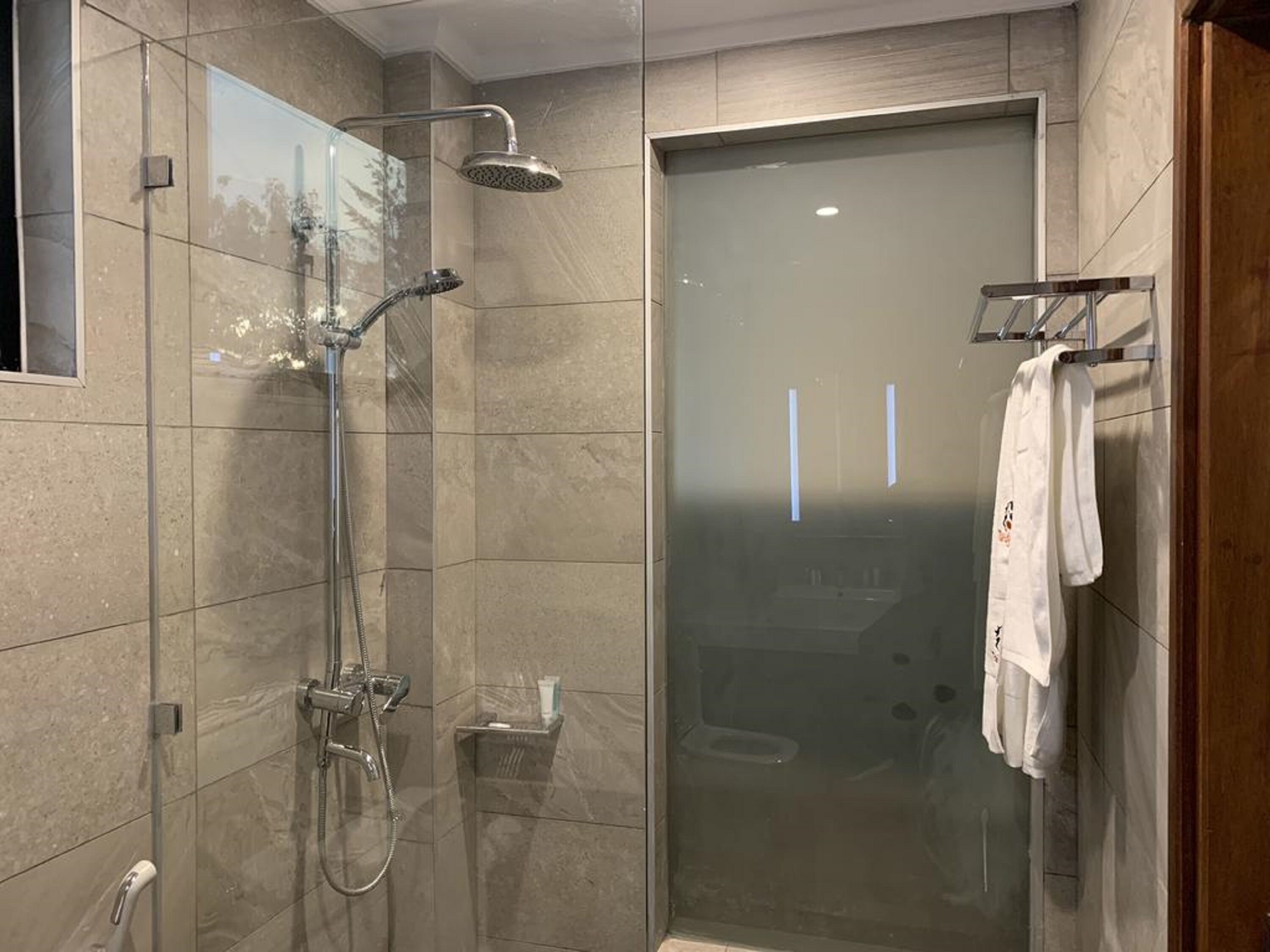 Ein modernes Duschbad mit Glastür, Handbrause und Handtuchhalter mit Handtuch.