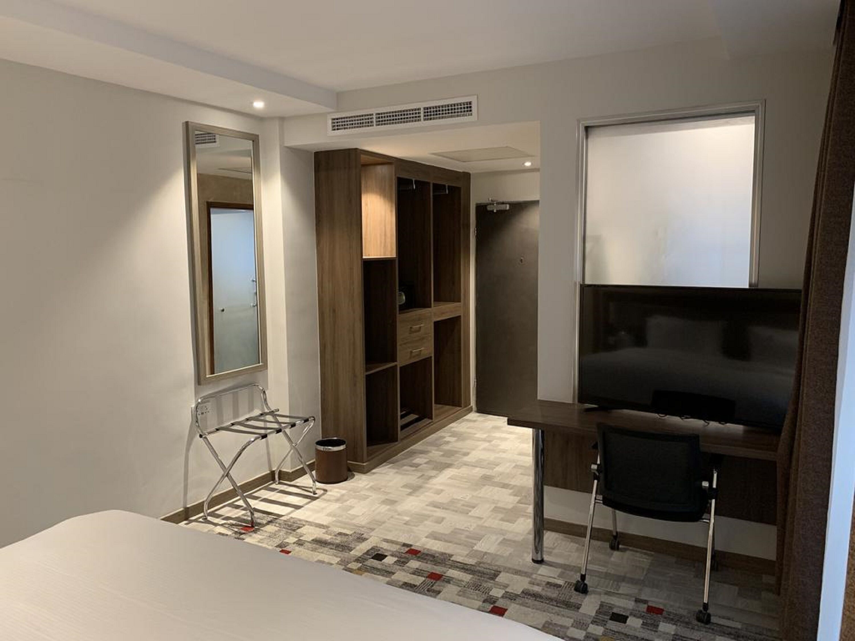 Ein Hotelzimmer mit Bett, Schreibtisch, Stuhl, Kleiderschrank und Spiegel.