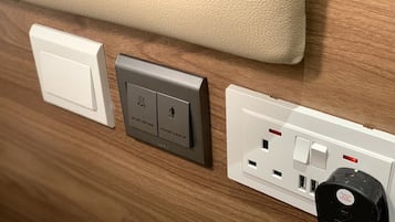 Een muur met een stopcontact, een lichtschakelaar en een deurbelknop.