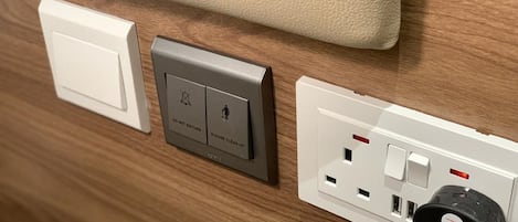 A wall with a power outlet, a switch, and a doorbell button.