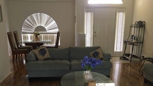 A living room with a glass coffee table, a sofa, and a dining area with chairs. - gulf coast haven !!! (Spring Hill)