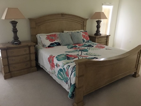 A bedroom with a wooden bed, two bedside tables, and a nightstand.