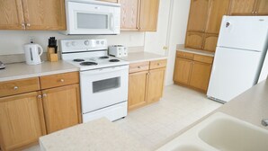 A kitchen with wooden cabinets, a white stove, a microwave, a refrigerator, and a sink. - gulf coast haven !!! (Spring Hill)