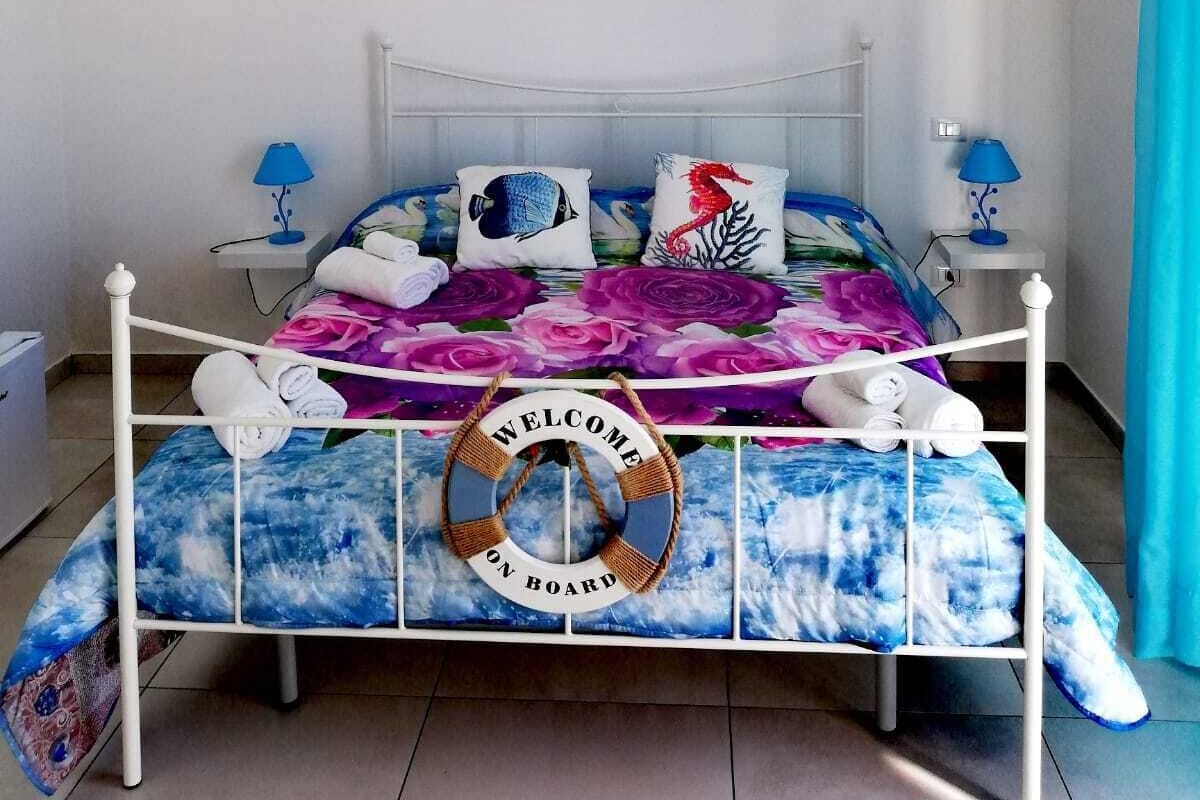 Ein Schlafzimmer mit einem Bett, einem an der Wand befestigten Kunstwerk, einem Willkommensschild und einer Pendelleuchte.