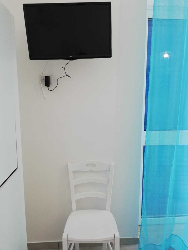 A white chair in front of a wall-mounted TV. - Coast to coast Salento sea rooms (Porto Cesareo)