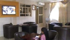 A room with leather chairs, a television mounted on the wall, and a window with curtains.
