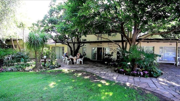Guests can relax in the tranquil courtyard, surrounded by lush gardens and shaded by trees.