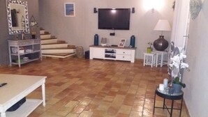 A living room with a TV, a staircase, a white sofa, and a coffee table.