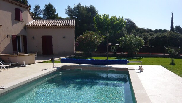 A rectangular swimming pool with clear blue water, surrounded by a tiled deck.