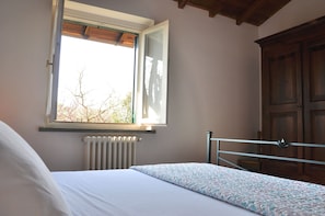 A bedroom with a bed, a window, a radiator, and a wooden wardrobe. - Montecasciano Girasole (Capranica)