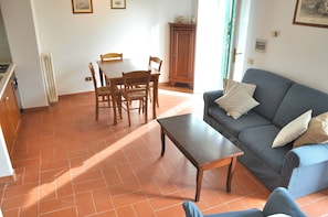 A living room with a sofa, a coffee table, and a dining table with chairs.