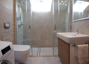 A modern bathroom with a glass-enclosed shower, a toilet, a sink, and a mirror. - Apartment Split Belvedere (Split)