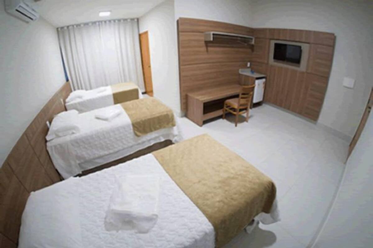 A hotel room with two beds, a desk, and a TV.